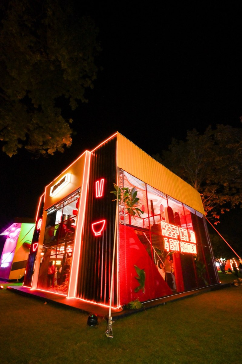 Contenedor de dos niveles de Ajinomen iluminado con neón rojo de noche en el Festival Estéreo Picnic